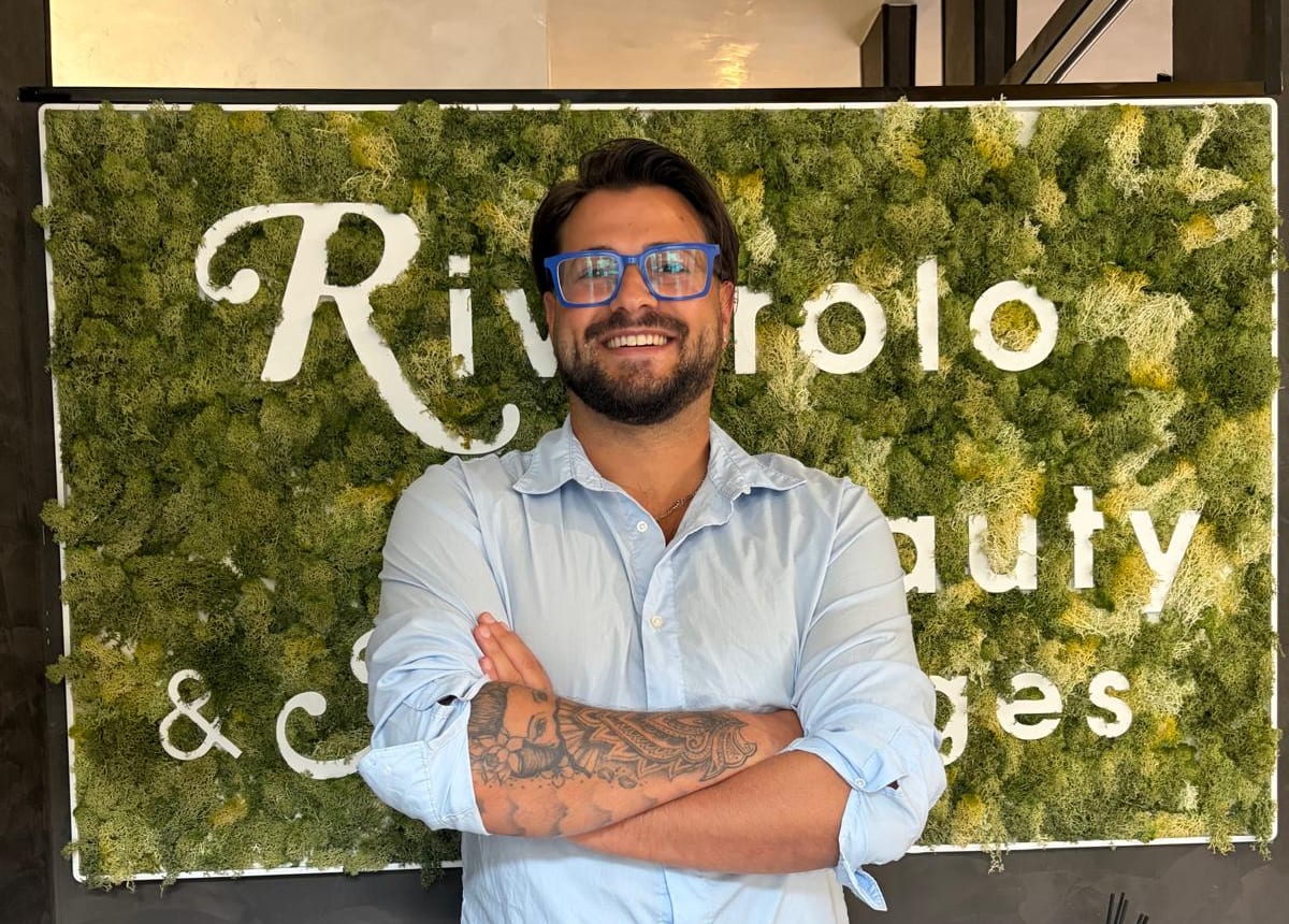 Andrea Camandona davanti alla parete verde con l'insegna Rivarolo Beauty & Massages